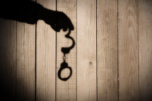 Male Hand with Handcuffs on Natural Wood Background, XXXL.